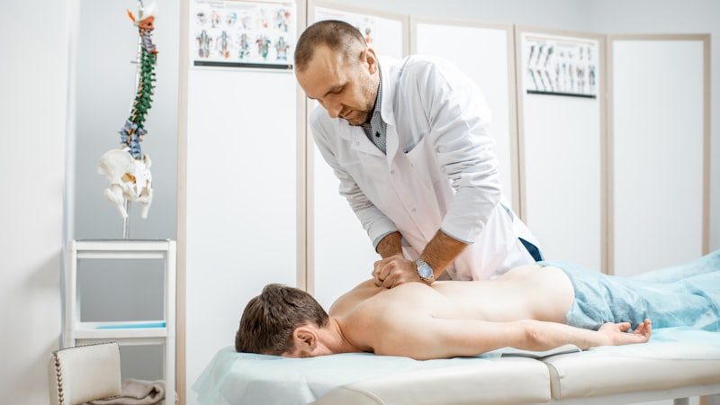 Chiropractor examining a patient's spine using a spinal model